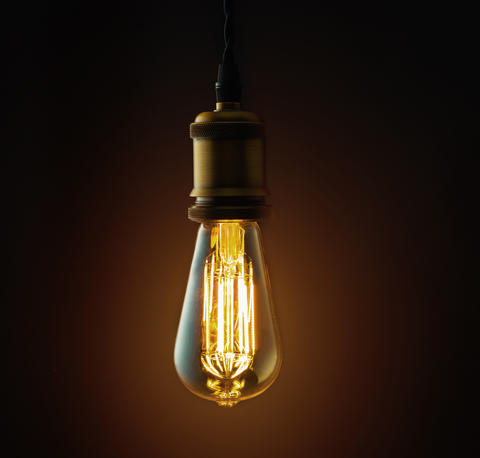 An old-fashioned Edison lightbulb hangs from a wire.