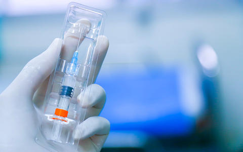 a latex gloved hand holds a syringe that has been loaded with medicine