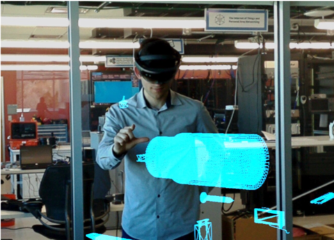 This is a photo of a man in an augmented reality headset looking at the hologram of an IED.