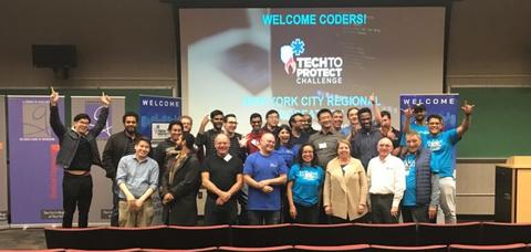 This image shows a group of people, some with their hands raised, standing in front of screen that says "Welcome Coders!", "Tech to Protect Challenge", and "New York City"