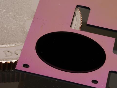 A flat pink device with a round black patch lies over a quarter.