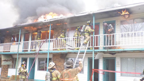 This image shows a motel on fire and firefighters responding.