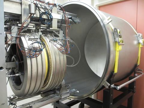 a large, hollow silver cylinder on a wheeled metal rack on the right, the guarded hot plate, another smaller cylinder festooned with wires that fits inside the larger cylinder is on the left