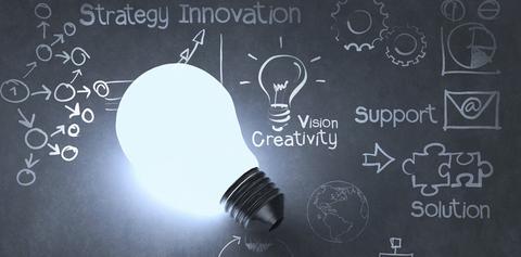 A lightbulb on a chalkboard, with the text "strategy innovation vision creativity support solution" surrounded by drawings of a lightbulb, gears, envelope, pie graphs, and the globe