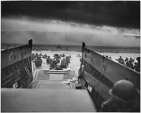 Photo taken from a boat during WWII: Europe: France; "Into the Jaws of Death - U.S. Troops wading through water and Nazi gunfire" Collection: Franklin D. Roosevelt Library Public Domain Photographs, 1882 - 1962