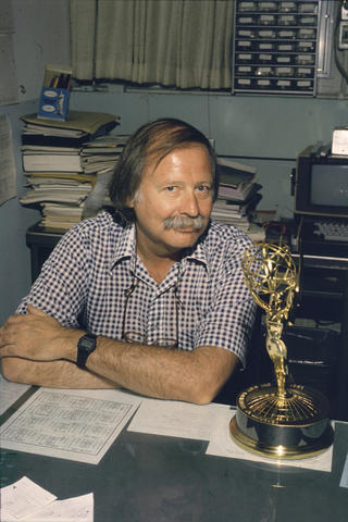 man seated at his desk with Emmy
