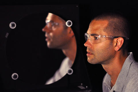 Man seen in profile in front of a circular mirror