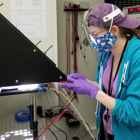 Woman wearing protective face covering works in a lab.