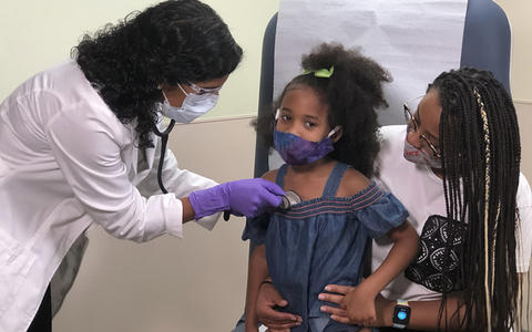 GMBC HealthCare System 2020 Baldrige Award Recipient in Health Care doctor listening to a toddlers heart that is sitting on her mother's lap.