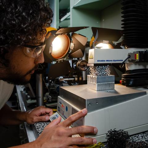 A man wearing safety goggles leans over a scientific device.