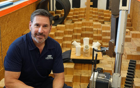 Adam Jacoff in the NIST Robot Test Facility in the obstacle course with a robot