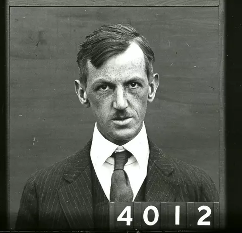 Caucasian man with a mustache wearing a suit and tie
