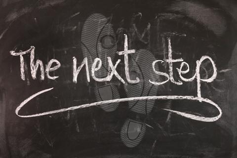 Footprints with "the next step" written on top in chalk.