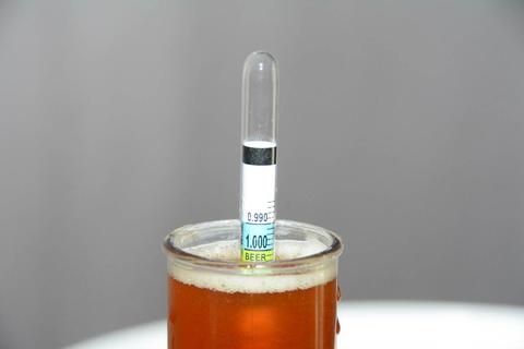 A glass tube floats vertically in a flask of amber-colored liquid.