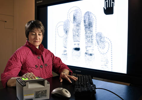 Mary Theofanos demonstrates NIST-designed fingerprint overlays on a fingerprint-scanning system in 2011.