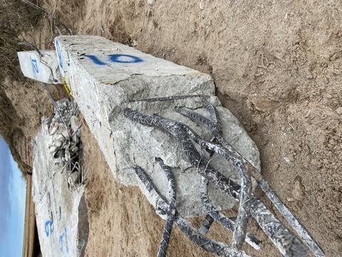 Broken concrete column with exposed rebar on the ground