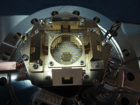 Ion trap is tiny chip held in place as part of a larger metal scientific device.