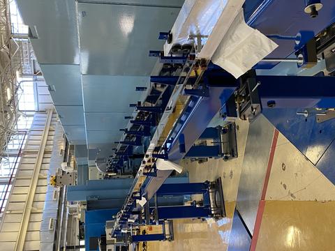 view of a long of neutron guides looking like steel rails inside of a large experiment hall