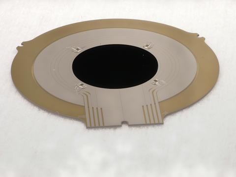 A flat disk has a black center and bronze around the outside.