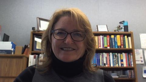 Headshot of Carolyn Schmidt with bookshelf in background.