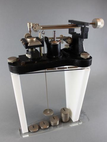 Scientific device has vertical frame with disk hanging inside over four cylinders of different heights.