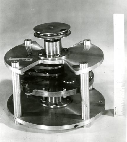 Scientific instrument has several layers of metal disks held together by four pins.