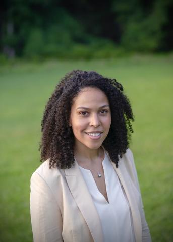 A woman poses for a head shot outdoors.