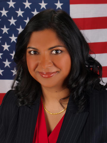 Pravina Raghavan poses with the American flag behind her.