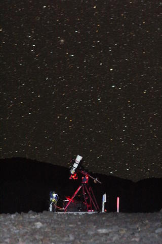 An instrument on a red scaffold stands in front of a starry night sky.