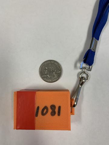 A numbered orange plastic box on a lanyard is shown with a quarter for scale.