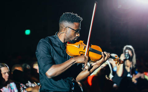 Photo of Kai Kight Quest for Excellence 33rd Keynote Speaker playing the violin in the audience.