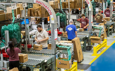 MidwayUSA employees assembling orders in boxes to ship to customers.