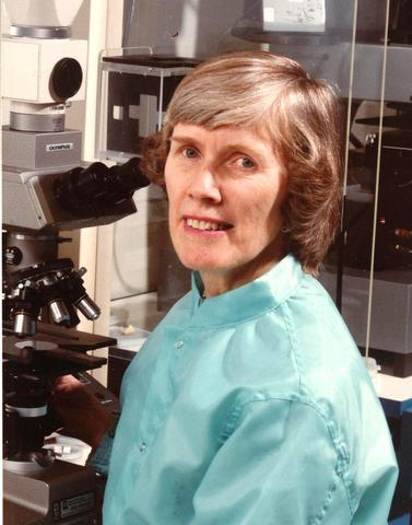 Frances Lloyd poses next to a microscope.