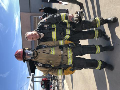 Person in firefighter gear stands with Dereck Orr outdoors