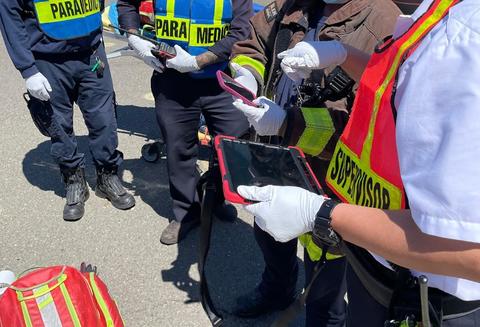 A first responder holding an iPad at the scene of an emergency