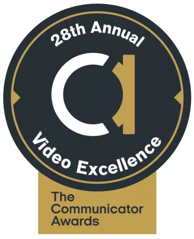 black circle. big white and gold lowercase a in the middle. Around the edges: 28th annual video excellence in white. Gold box at bottom that includes black words: The Communicator Awards