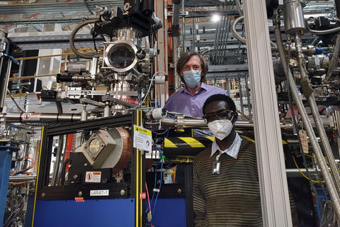 Two men standing amid high tech metallic instruments.