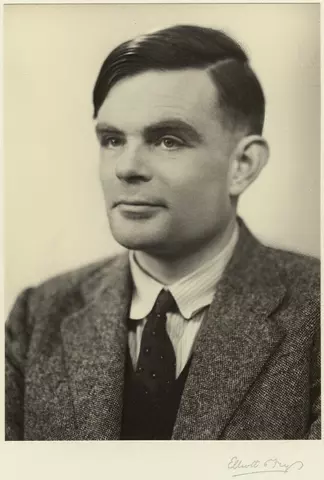 black and white headshot from chest up. Man is wearing a suit jacket and tie