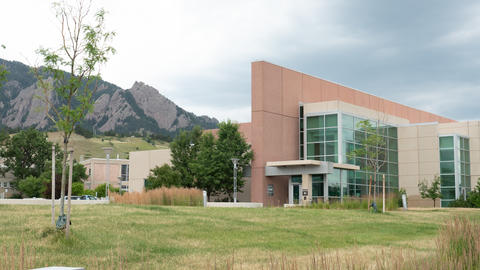 An angular office building is to the right, with lower building to the left and mountains in the background.
