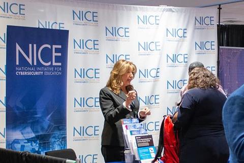 Image of Davina Pruitt Mentle talking with a visitor to the NIST NICE booth at a NICE Conference in Summer 2022