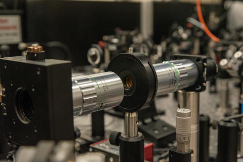 Optical equipment includes a horizontal metal tube with a black cap on the end and a hole for light to shine through.