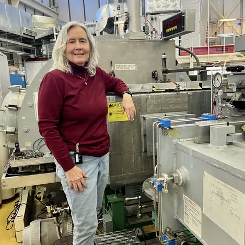 Susan Krueger poses in the lab, resting one arm on a large piece of scientific equipment. 