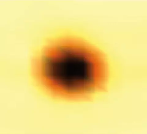 A blurry dark circle lightens at the edges on a yellow background.