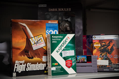 Boxes of old software stand on a shelf, including a flight simulator, Dark Souls II and a Kaspersky anti-virus product.
