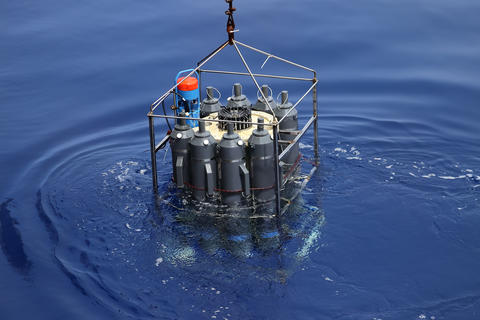 Water sampling device shown suspended into tranquil water from a cable