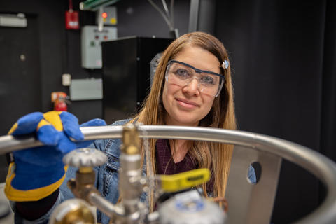 Maria Munoz poses in the lab, wearing safety goggles and heavy gloves. 