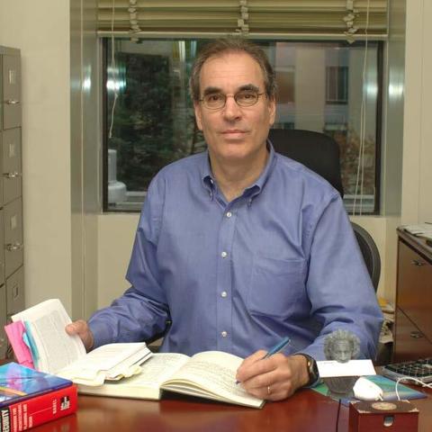 Andrew Persily poses at his desk, with open books in front of him.