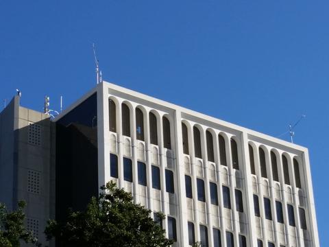 Photo of the exterior upper portion of Caltech Hall showing weather stations on the corners of the roof. 