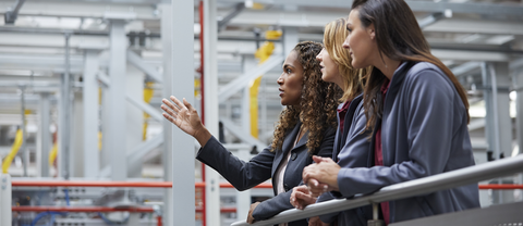 Engineers discussing at railing in car plant 