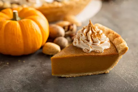 Photo of slice of pumpkin pie and a small pumpkin